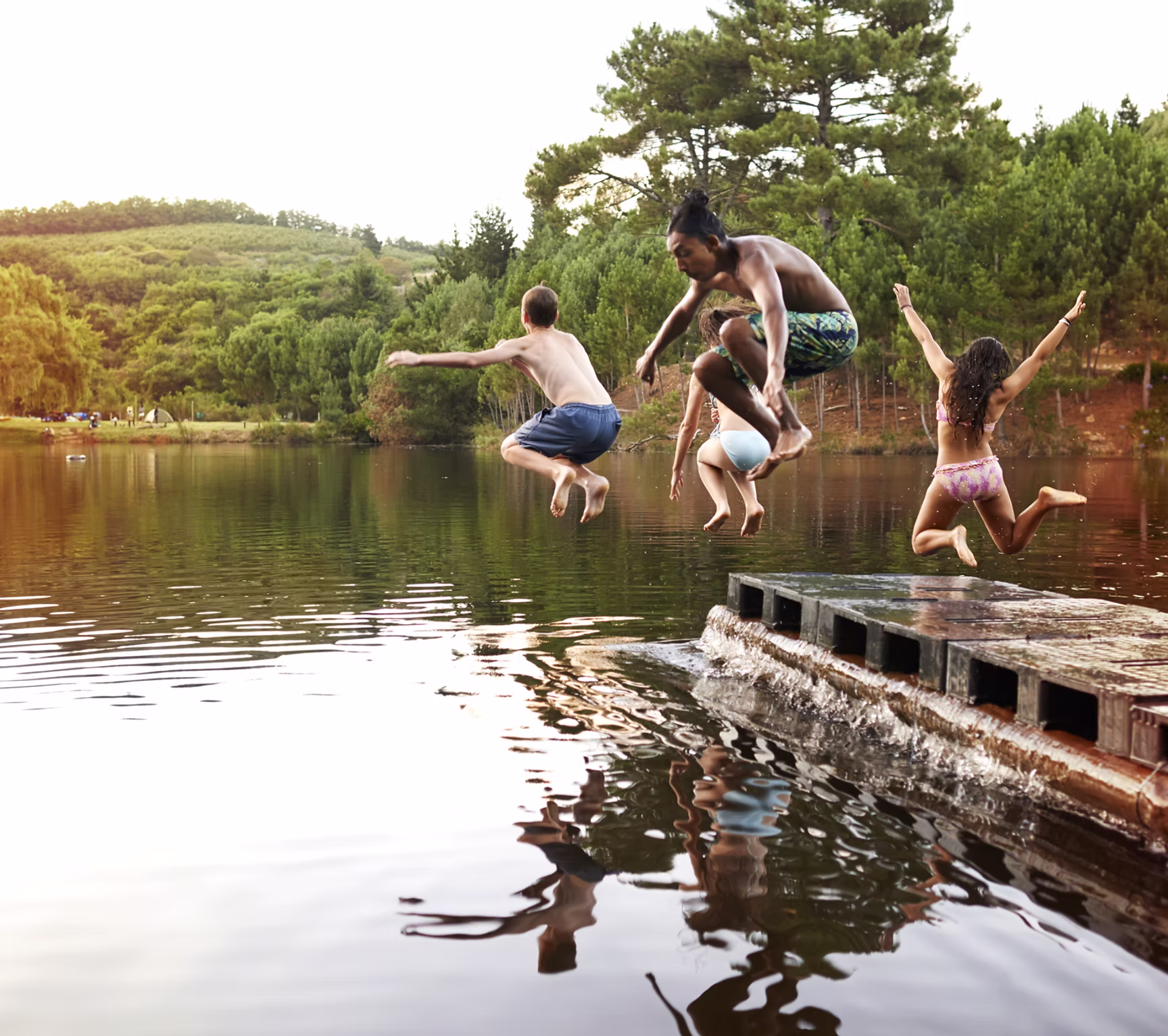Photo of kids jumping into a lake at summer camp
